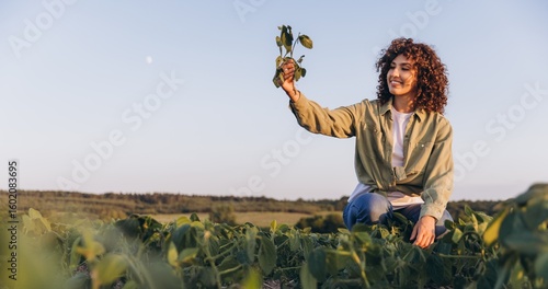 Foto Young agronomist woman holding soybean plant in cultivated field