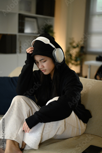 Canvas Print Sad teen girl in a hoodie and headphones, feeling overwhelmed or anxious