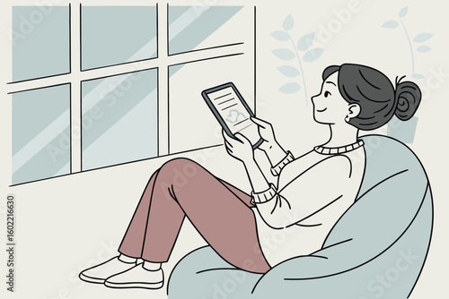 Relaxed woman reading on a tablet while sitting comfortably in a stylish bean bag chair near a large window