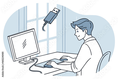 Man working at a computer with a USB drive hovering above his workstation during a bright day in a modern office setting
