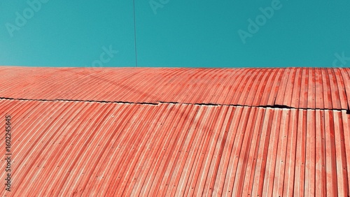 Red corrugated metal roof against a clear blue sky
