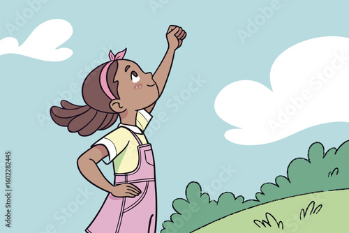 Young girl proudly raises her fist while standing on a grassy hill under a blue sky with clouds during daytime, embodying a spirit of determination and empowerment