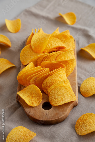 Bacon flavoured potato chips on a wooden board, side view.
