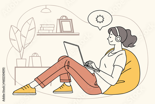 Young woman with headphones works on laptop while sitting comfortably in a bean bag chair in a cozy and modern indoor space