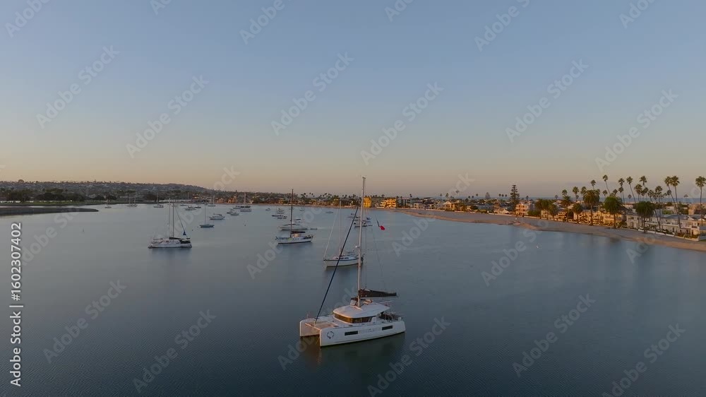 Aerial view of boats scattered on still, blue waters reflecting the sky, with sandy beaches and palm trees under soft sunlight, San Diego, California, United States. Aerial view of boats scattered on still, blue waters reflecting the sky, with sandy beaches and palm trees under soft sunlight, San Diego, California, United States.