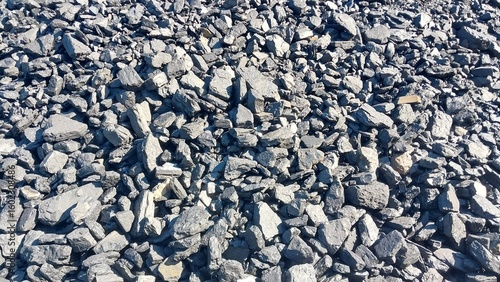 A close-up view of a rocky surface covered with small, irregularly shaped stones and pebbles in various shades of gray and white, under natural daylight