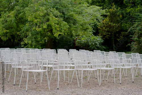 White chairs arranged in rows for outdoor event in park