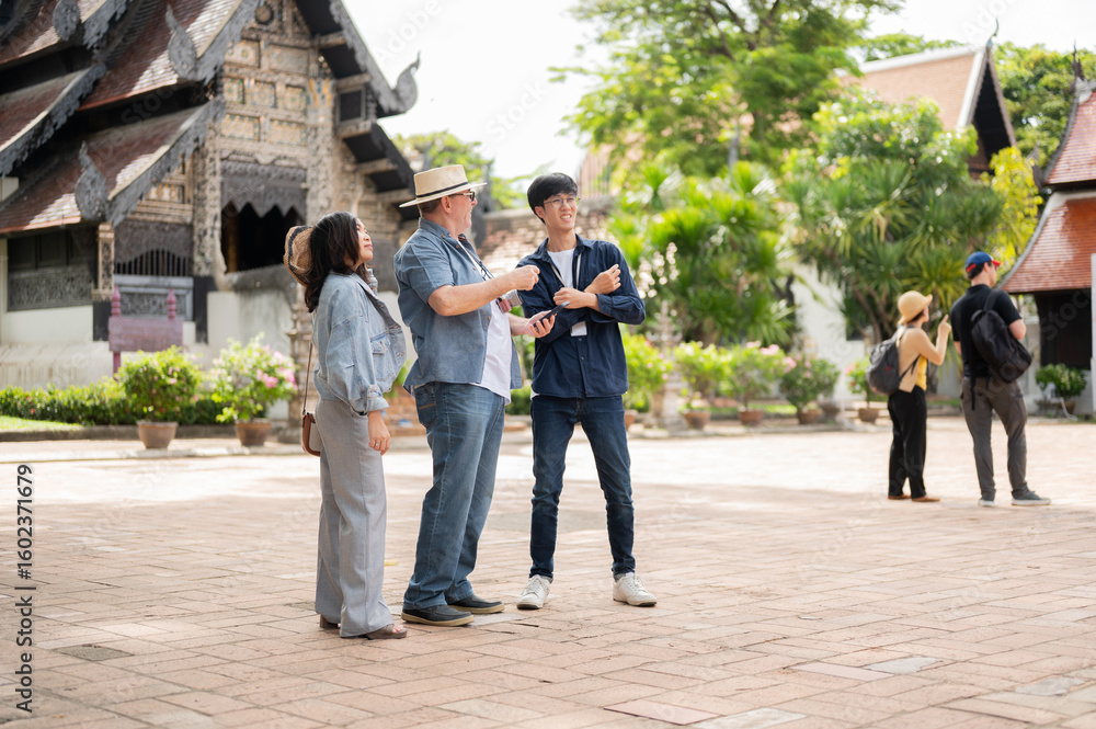 Obraz premium Old white man and woman talking with guide while standing and looking around buddhist temple grounds