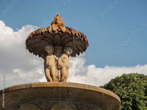 Canvas Print Ornate stone fountain with cherubs under a blue sky.
