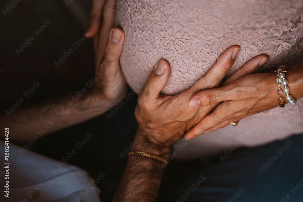 Fototapeta premium Hands Gently Cradling a Pregnant Belly in Warm Embrace