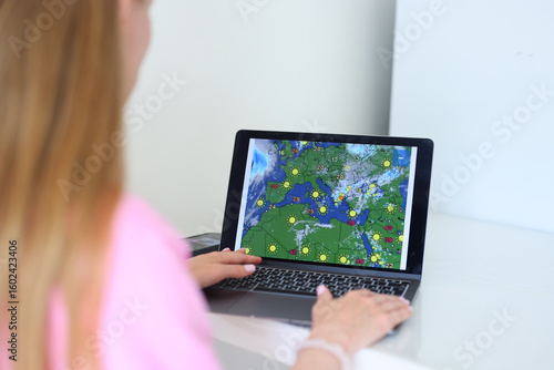 Wallpaper Mural Woman checking weather forecast on laptop, real-time radar, climate tracking, weather planning Torontodigital.ca