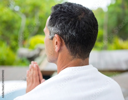 Person meditating from behind with hands in prayer position, conveying spiritual peace and outdoor mindfulness.