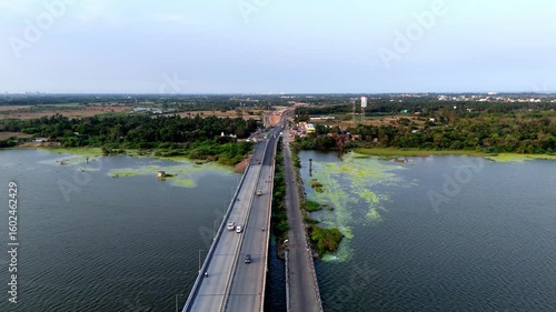 Wallpaper Mural Drone shot capturing a vital road bridge over a lake in Chennai, showing light traffic and lush green surroundings extending to the horizon. accented by natural green aquatic growth Torontodigital.ca