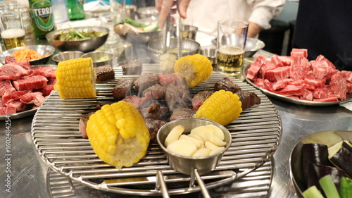 Korean Barbecue Grill Setup with Fresh Beef, Side Dishes, and Vegetables at Traditional Restaurant Table