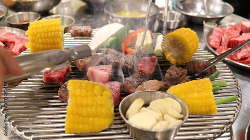 Korean Barbecue Grill Setup with Fresh Beef, Side Dishes, and Vegetables at Traditional Restaurant Table