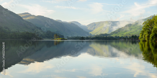 Ullswater in The Lake District on a calm summer morning with reflections in water.