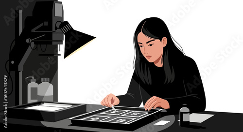 The artist meticulously working on photographic prints in her darkroom illuminated by the lamp and focusing on the details of the image development