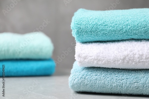 Stacks of soft towels on grey marble table, closeup. Space for text