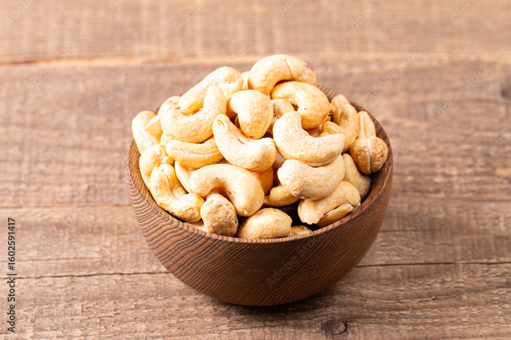 Fototapeta premium Organic roasted cashew nuts in a wooden bowl. Top view. 