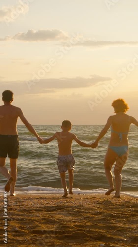 A cheerful family sprints along the sandy shore eager to dive into the ocean's embrace as the sun sets casting a golden glow.
