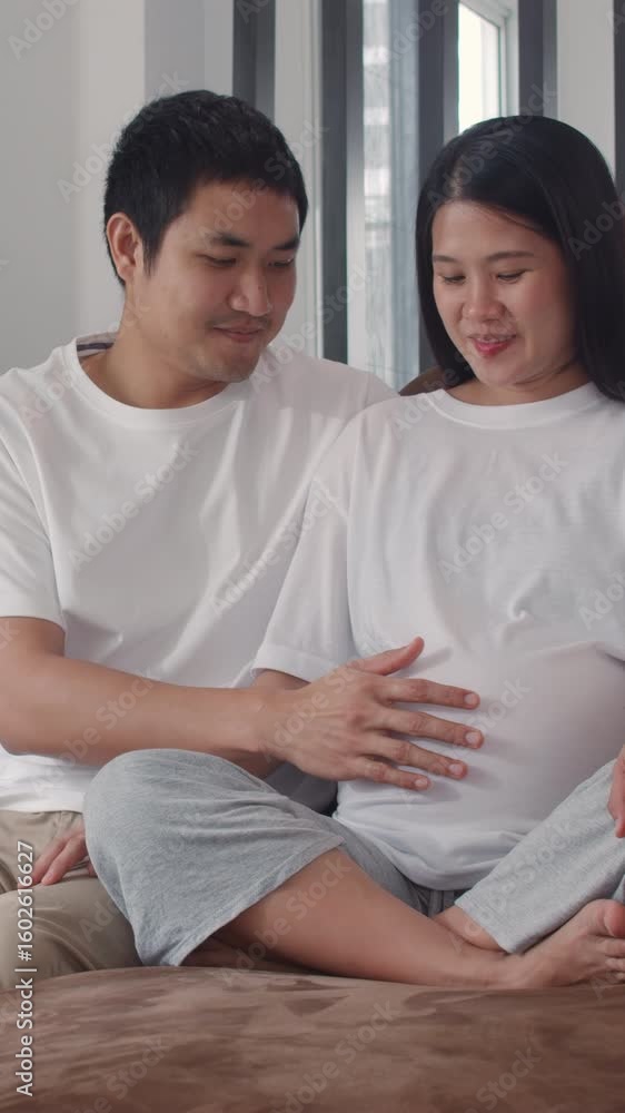 Vertical Screen : Young Asian Pregnant couple man touch wife belly talking with child. Mom and Dad happy smile peaceful while take care baby, pregnancy lying sofa in living room at home. Slow motion. Vertical Screen : Young Asian Pregnant couple man touch wife belly talking with child. Mom and Dad happy smile peaceful while take care baby, pregnancy lying sofa in living room at home. Slow motion.