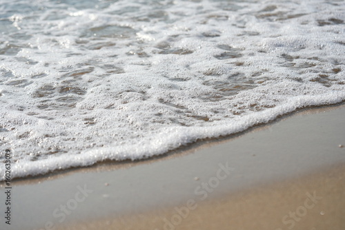 sea waves rolling on sandy beach – close-up shoreline  sea waves gently rolling onto the sandy beach. clear water, foam, and soft motion create a calming natural seascape. ideal for vacation 