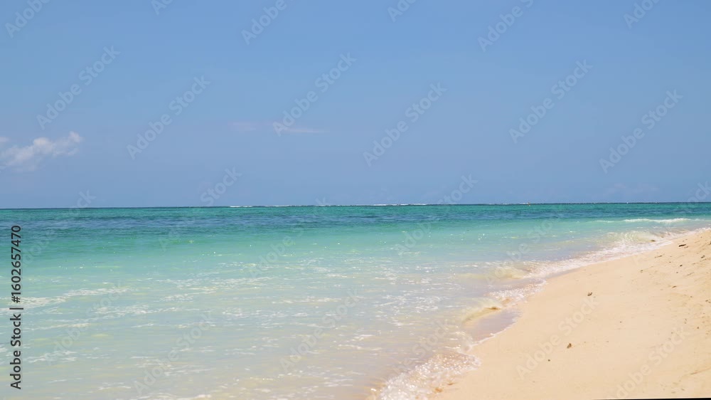 Serene tropical beach.Perfect summer vacation background for travel and relaxation concepts. Gentle waves of the azure ocean lap against the soft golden sand on a beautiful sunny day Serene tropical beach.Perfect summer vacation background for travel and relaxation concepts. Gentle waves of the azure ocean lap against the soft golden sand on a beautiful sunny day