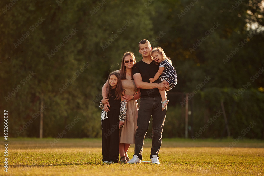 Obraz premium The family of husband, wife and two daughters on the field outdoors
