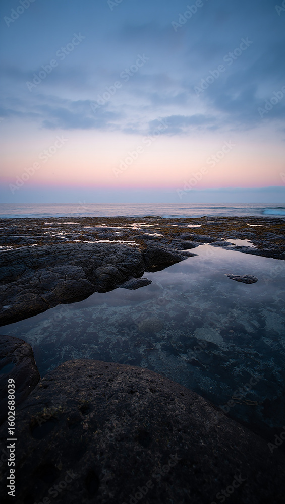 Fototapeta premium Serene coastal landscape at twilight with calm water and colorful sky