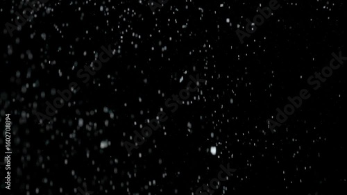 Many silver glitter particles powder falling from above, floating on empty black contrast background. Slow motion.