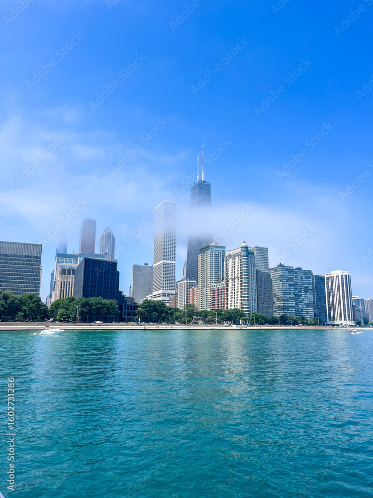 Obraz premium Beautiful sunny day in Chicago, Illinois. Views of the skyline above the bright blue sky and water in Lake Michigan.