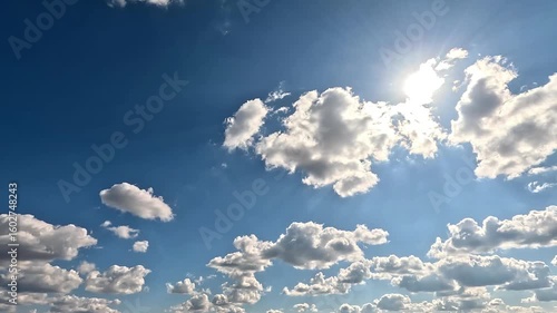 Bright Clouds in the Daylight Skies. 4K video (Ultra High Definition) of cloudscape and bright sun. Sky and clouds Timelapse. Sun shines through the clouds on the blue sky background.