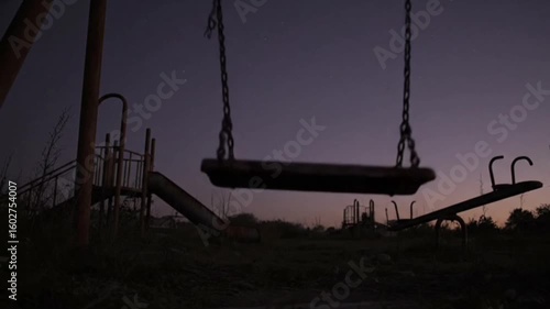 An abandoned playground at dusk. A single swing moves slowly in the breeze. Rust creaks echo through the emptiness.