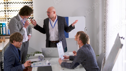 Foto A serious, angry company executive asks a subordinate for a progress report