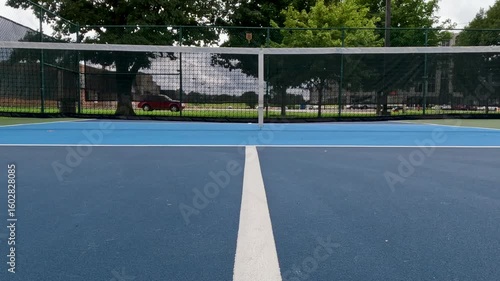 Wallpaper Mural Outdoor Pickleball Courts. Surface level, stationary view of an empty pickleball court. Centerline view, looking towards the net. Public city park setting with cloudy blue Summer sky. Torontodigital.ca