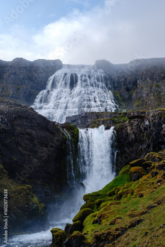 Majestic waterfall cascading down rocky cliffs in Icelands scenic landscape