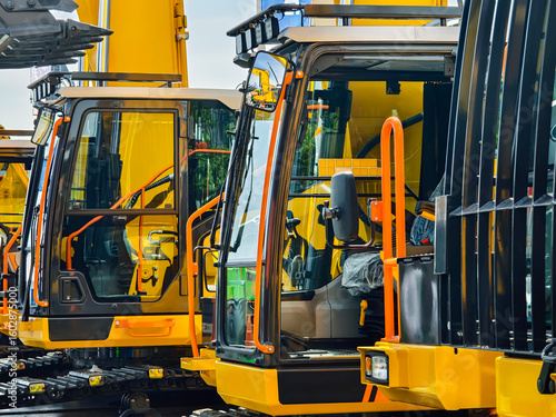 Heavy machinery lined up for inspection at a construction site during daylight hours