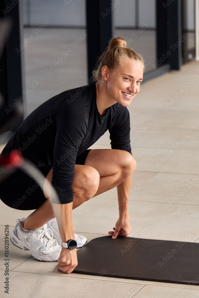 Fototapeta premium Smiling woman preparing fitness mat for home workout session