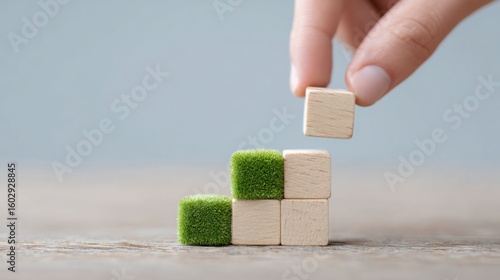 A hand is holding a stack of wooden blocks, with one block being green