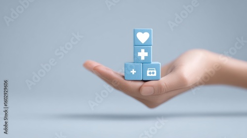 A hand holding a stack of blue cubes with a heart and a cross on top