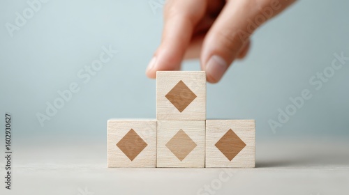 A hand is touching a stack of wooden blocks