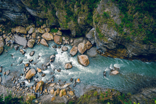 High-angle view of forest and river flowing through Taroko National Park, Taiwan. Clear blue water streams over rocks with moss in the crevices of the mountain. Idea for a nature background.