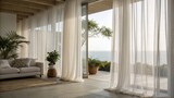 Bright living room with sheer white curtains, indoor plants, and a view of the ocean through large glass doors opening to a wooden deck.