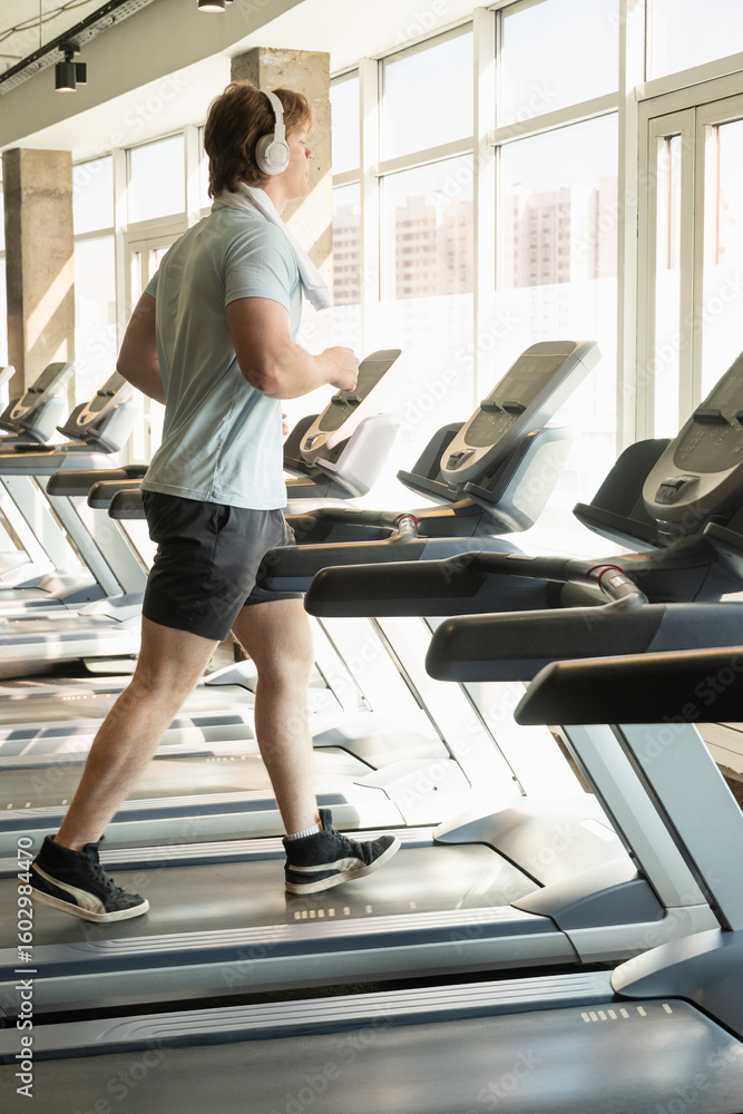 Fototapeta premium Running, exercise and young man running track, warming up on treadmill at gym. Cardio workout. Close up.