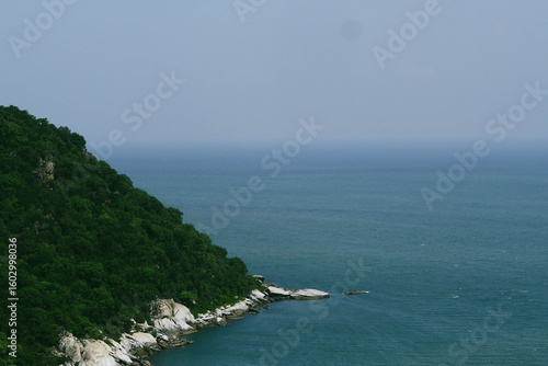 Green hillside meets blue ocean water.