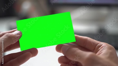 Close-up of a person's hands holding a green screen business card mockup