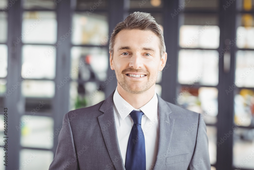 Fototapeta premium Business professional standing in modern office wearing gray suit and navy tie with glass panels
