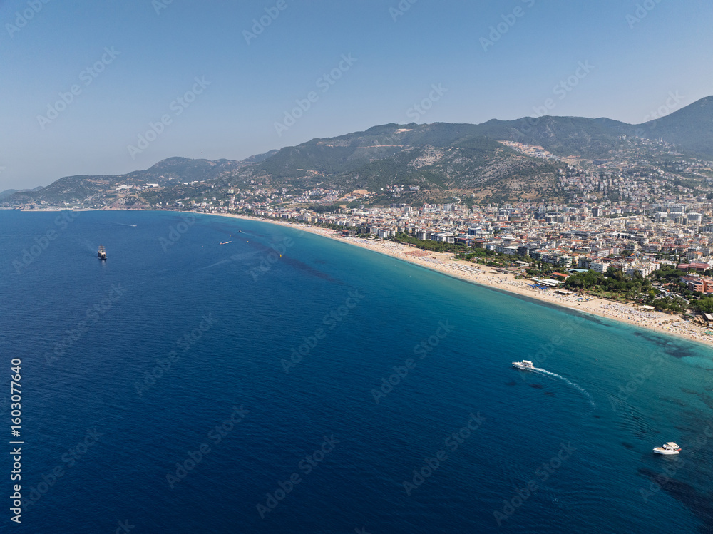 Fototapeta premium Aerial drone view of Cleopatra Beach in Alanya, Turkey. Alanya turquoise sea, sandy beach, cliffs, hills with caves, and the coastline during sunny summer day from above. Summer Mediterranean Sea.
