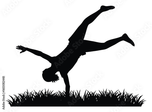 Silhouette of a young boy doing a cartwheel on grass with energy and enthusiasm depicting joy and freedom