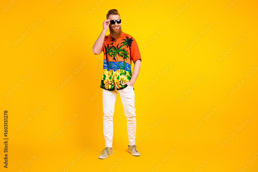 Fototapeta premium Stylish young man in vibrant tropical shirt on yellow background showing casual style and summer travel vibes